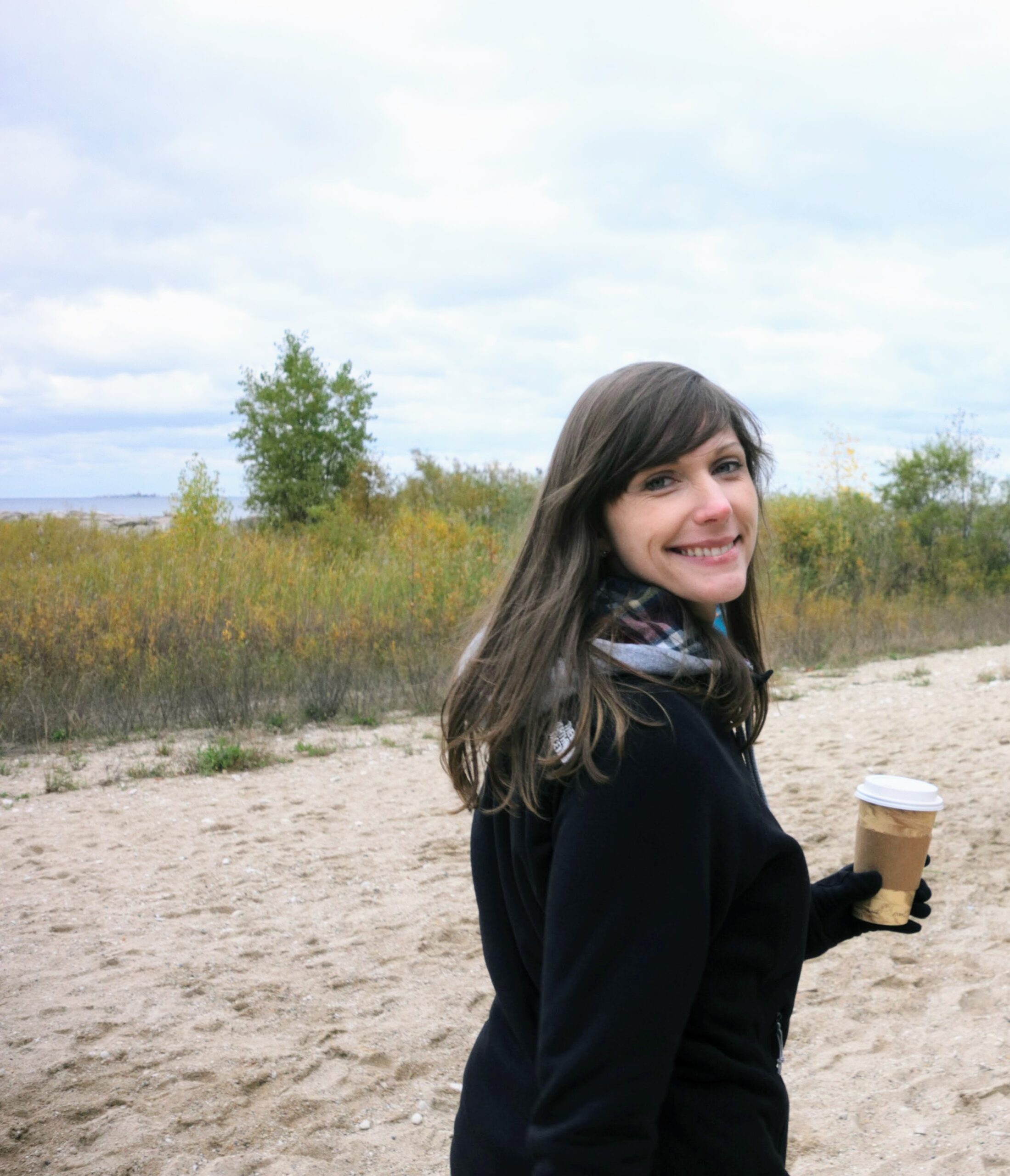 woman holding coffee by the lake